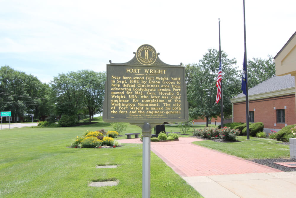 Bronze historical marker for Fort Wright on a lawn with a brick path and flags; plaque notes Fort Wright was built in 1862 by Union troops to defend Cincinnati.