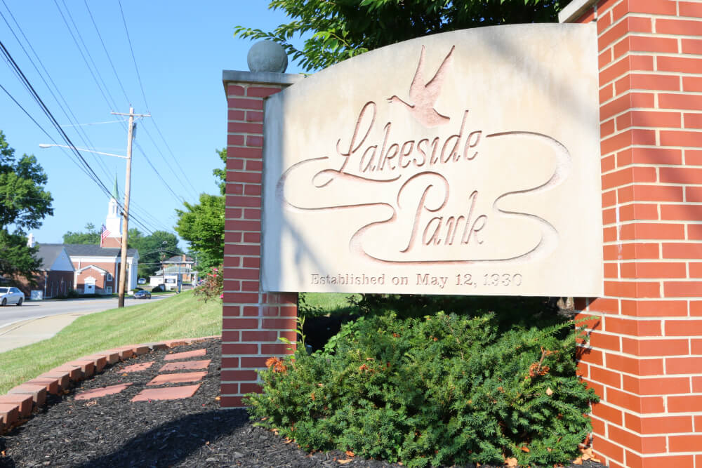 Lakeside Park | Pediatrics Of Florence Lakeside Park sign carved in stone between red brick pillars, with landscaping and a bird motif above the script.
