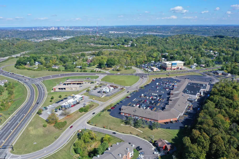 Taylor-Mill-Kentuckyjpg | Pediatrics Of Florence Aerial view of a highway interchange looping through a suburban commercial area with a large parking lot and surrounding green trees.
